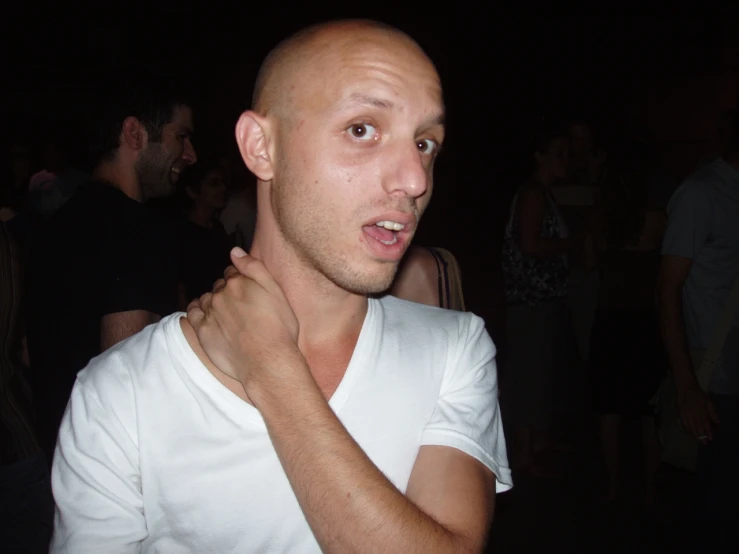 a bald man in white shirt holding a banana