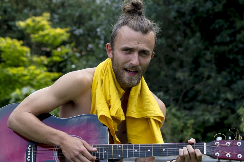 a man in yellow bandana holding an acoustic guitar