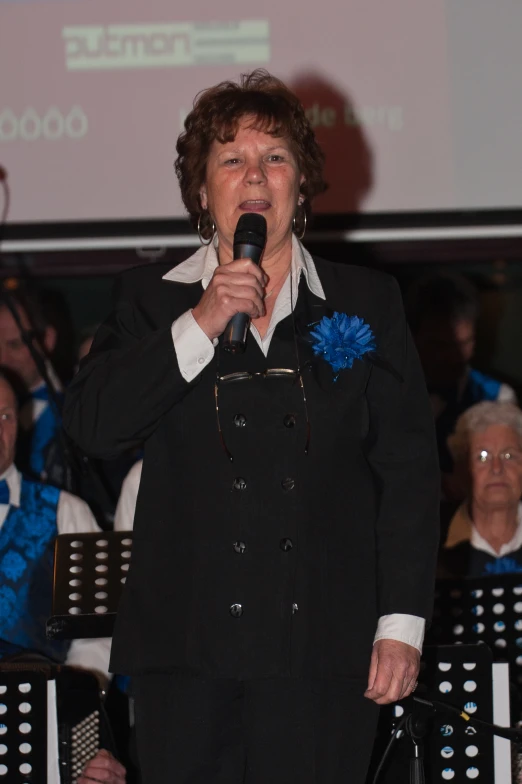 a woman singing into a microphone in front of an audience