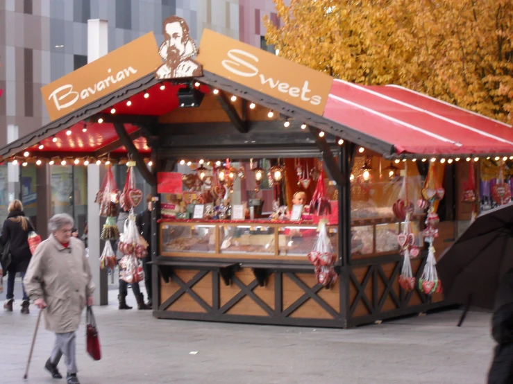 people walking around the streets next to a street side candy shop