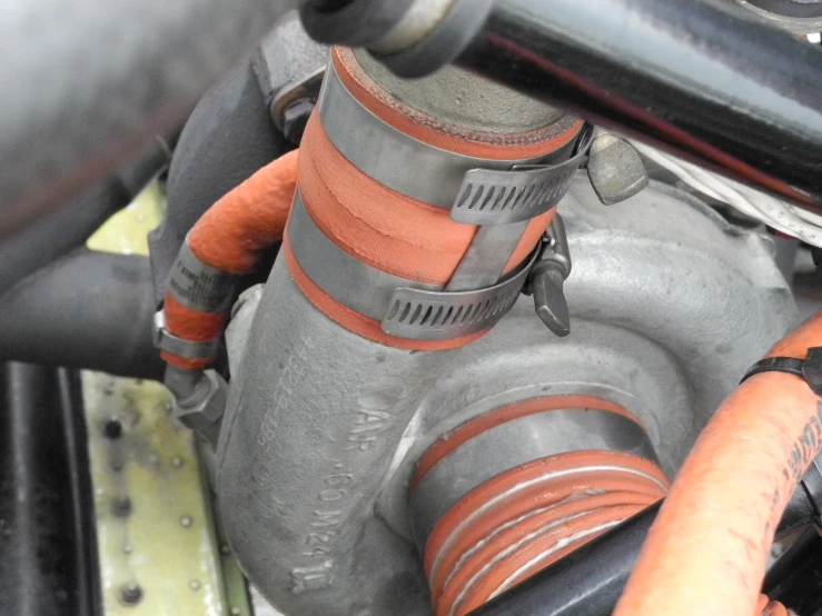 a gray and orange pipe attached to the side of a machine