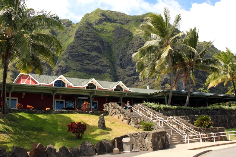 a small, tropical house on a grassy hill