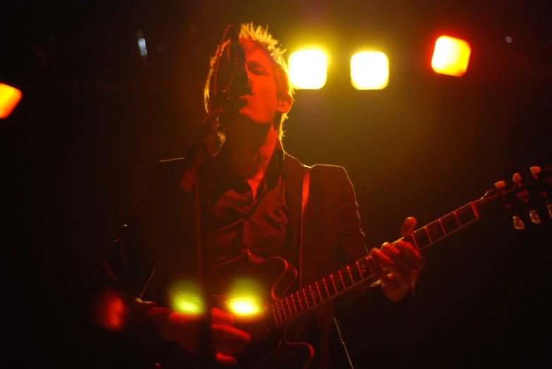 a young man playing an electric guitar on stage