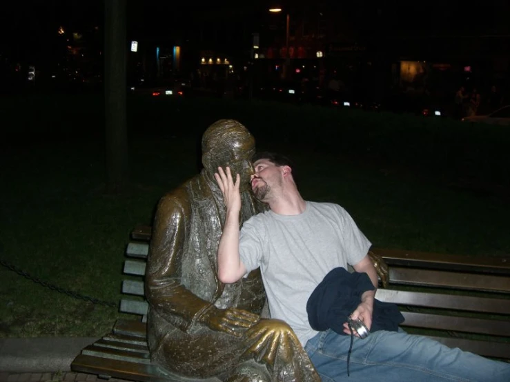 a man sitting next to a statue talking on a phone