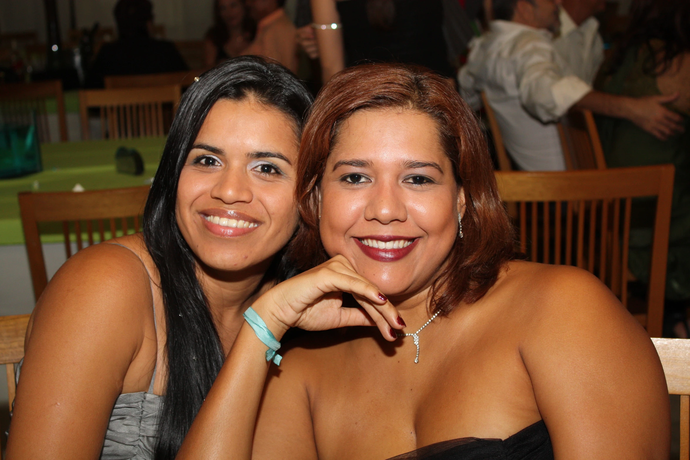 two women smiling and standing together with people watching them