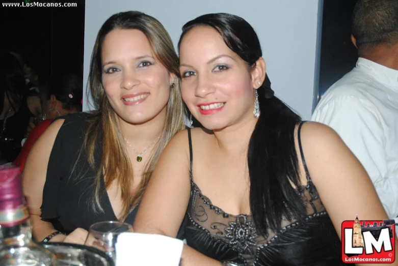 two young woman sit smiling at an event