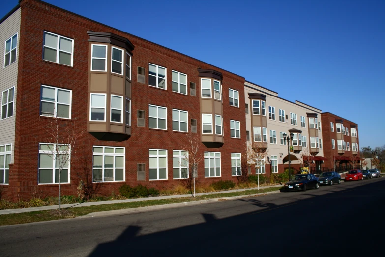 large brick apartment building with cars parked on the side