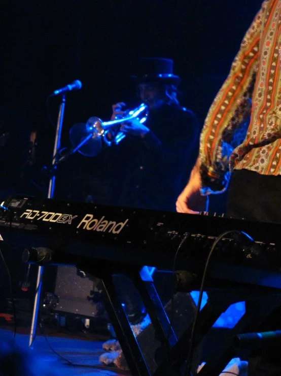 two people playing keyboards in a dark room