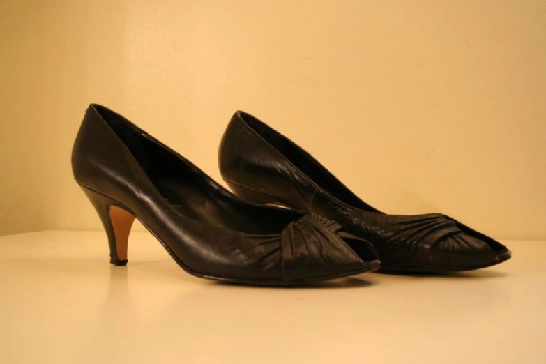 two women's black heels sit on a table