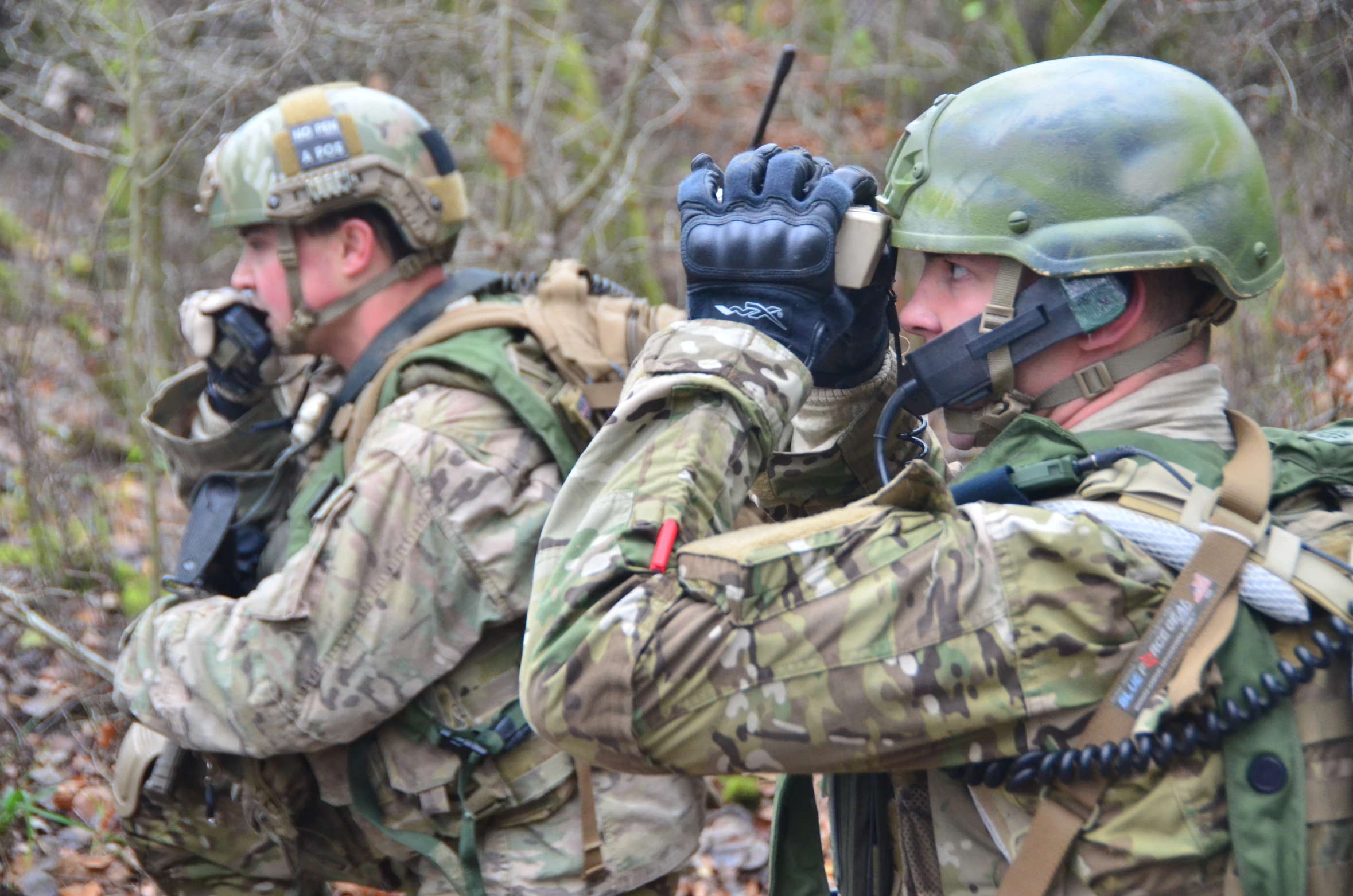 two men in military gear holding guns up