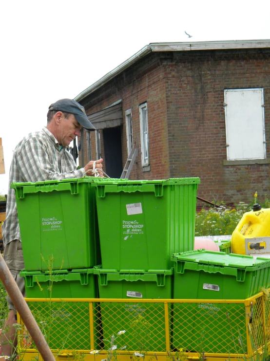 man in the yard putting up a new green crate