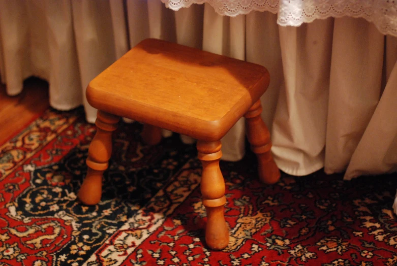 a small wooden stool in front of a window