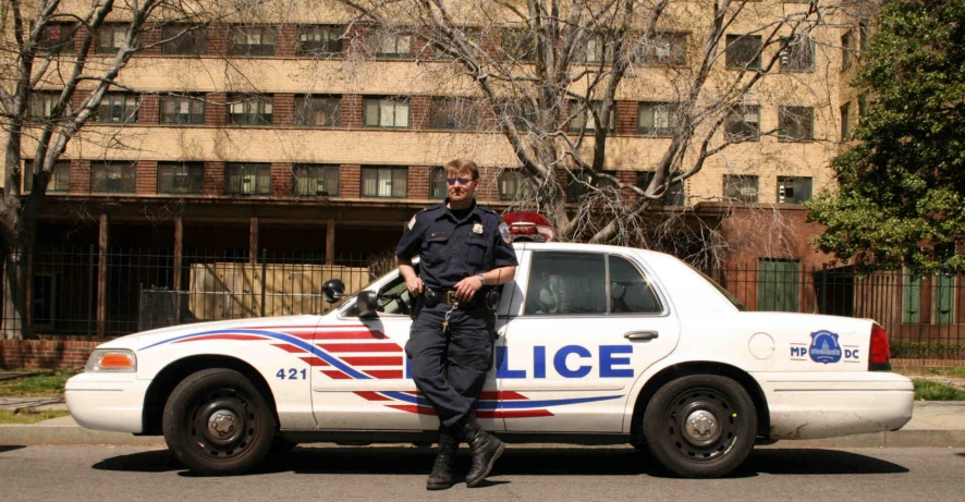 a police officer leaning on a white car