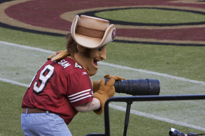 man wearing costume taking a po of his mascot on the sidelines