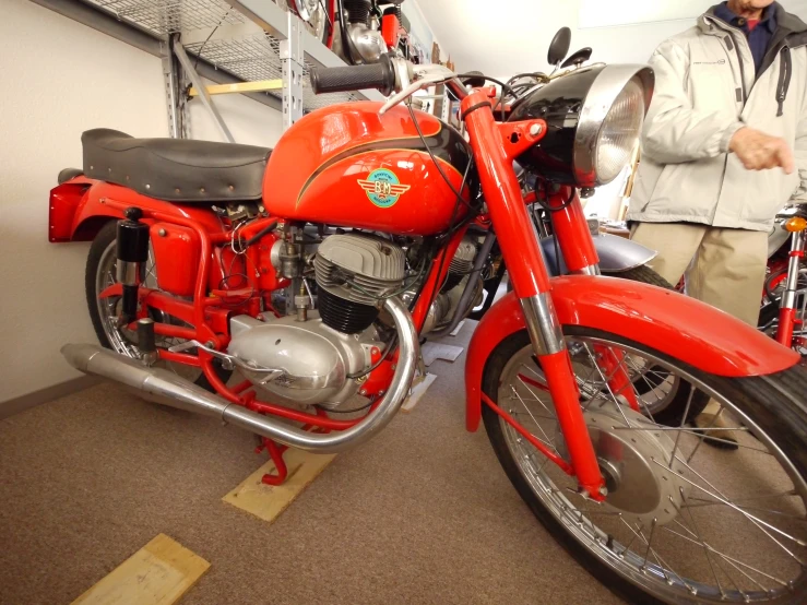 a man is next to a red motorcycle