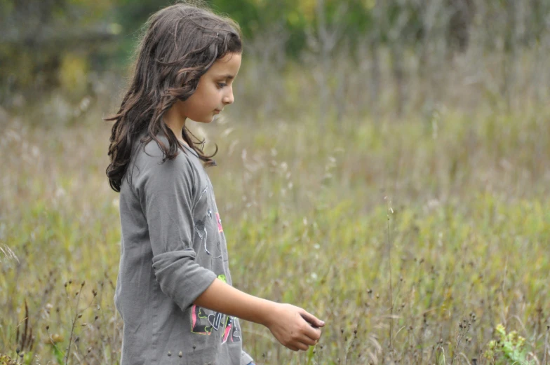 a little girl is standing in some tall grass