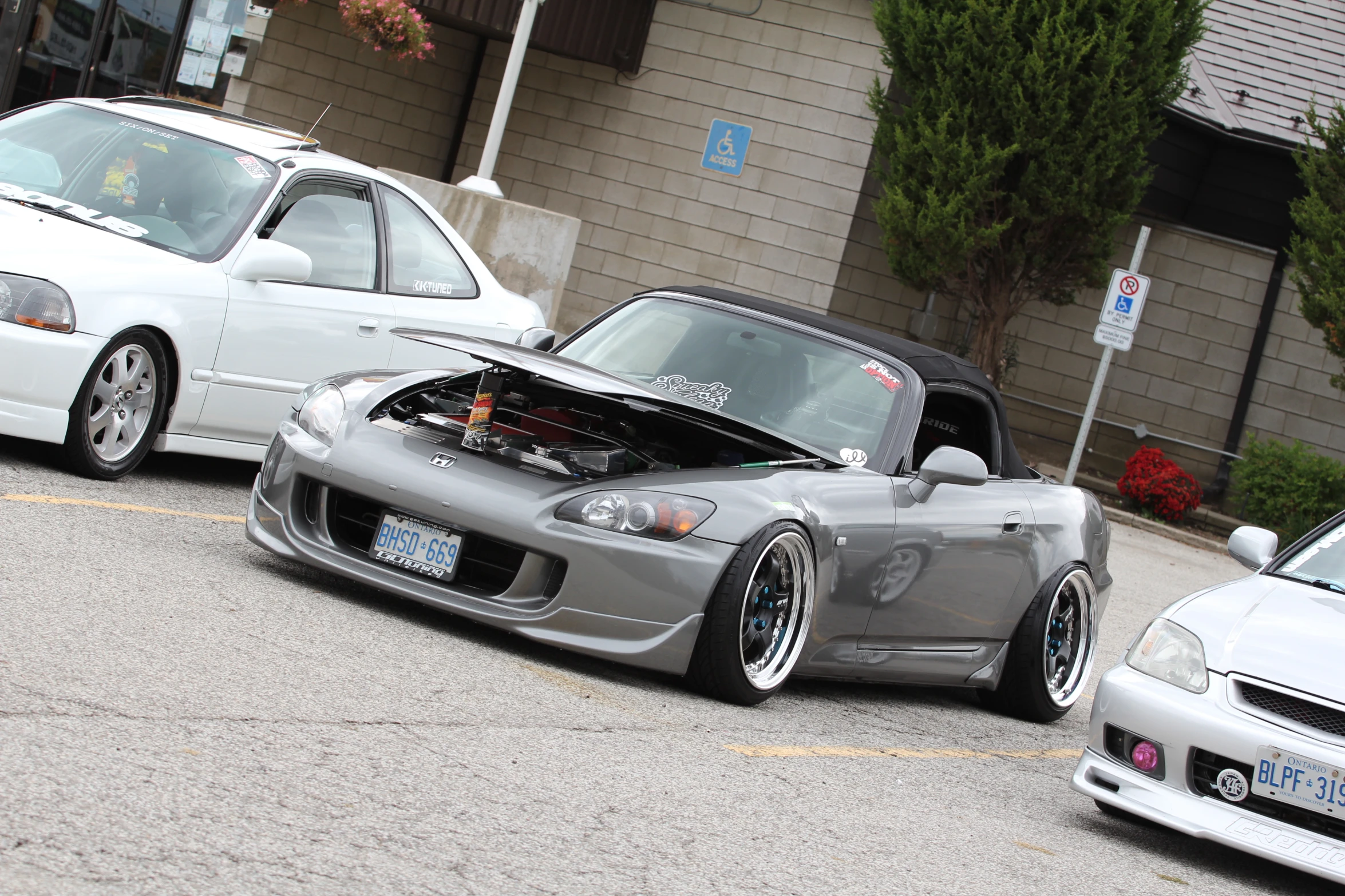 two cars sitting in the street, one being under a hood