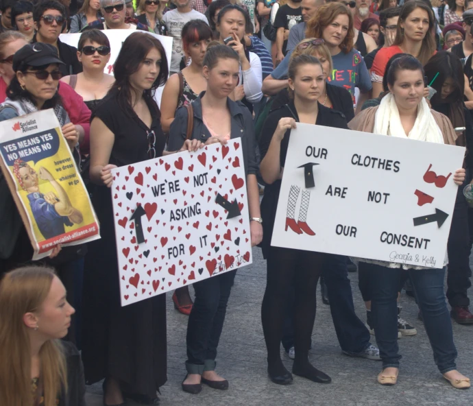 group of people holding protest signs with words our clothes are not conscient