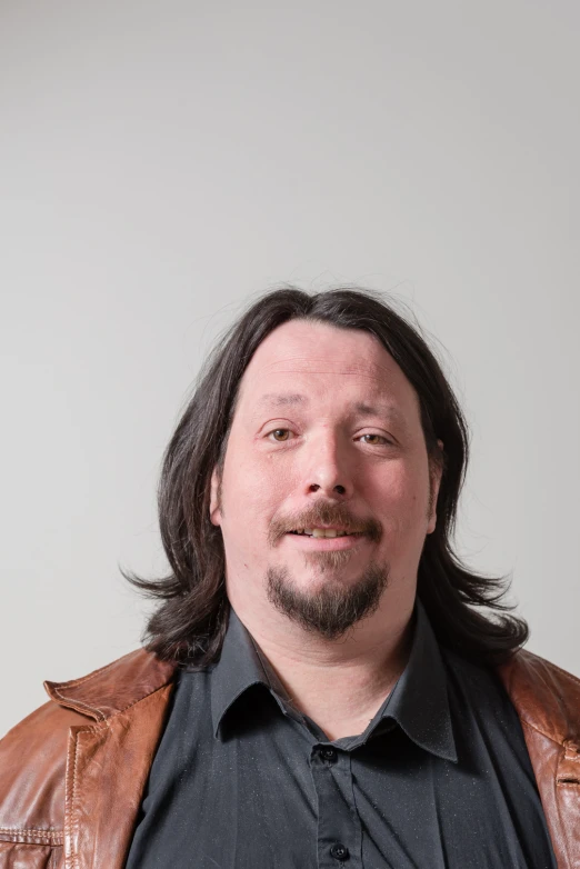 a man with a brown leather jacket posing for a picture