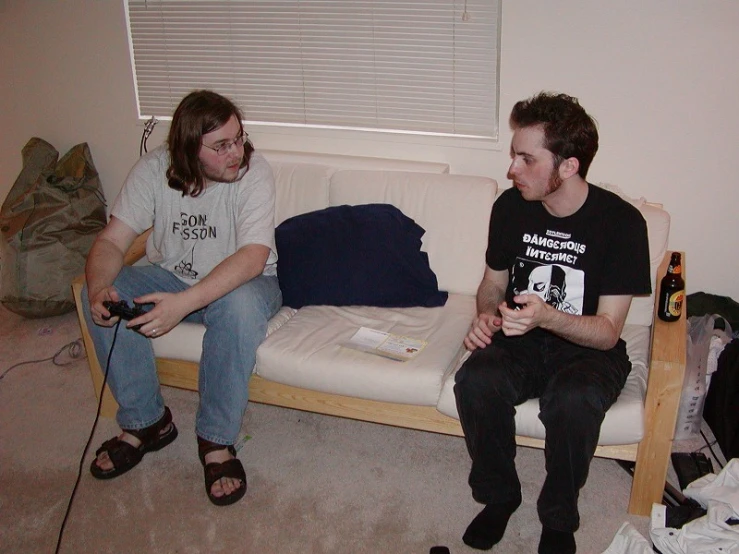 two young men sit on a bench in front of an empty couch