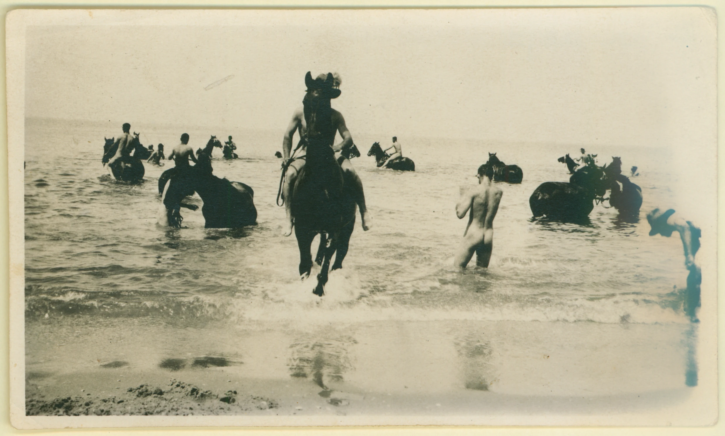 several people on horses in the water near a beach