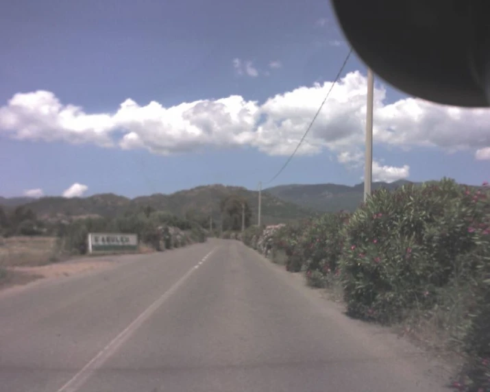 a car drives down an empty road surrounded by trees and flowers