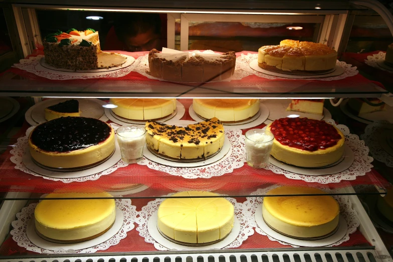 a variety of pies are behind glass