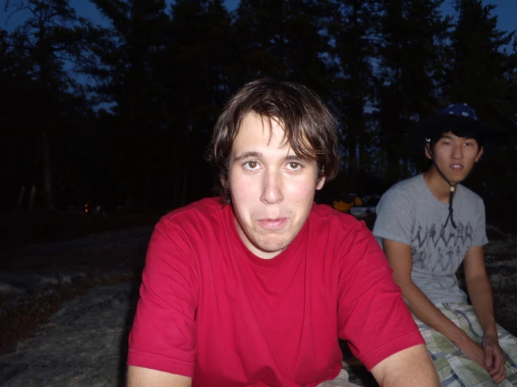 a young man looks at the camera while sitting in front of another man