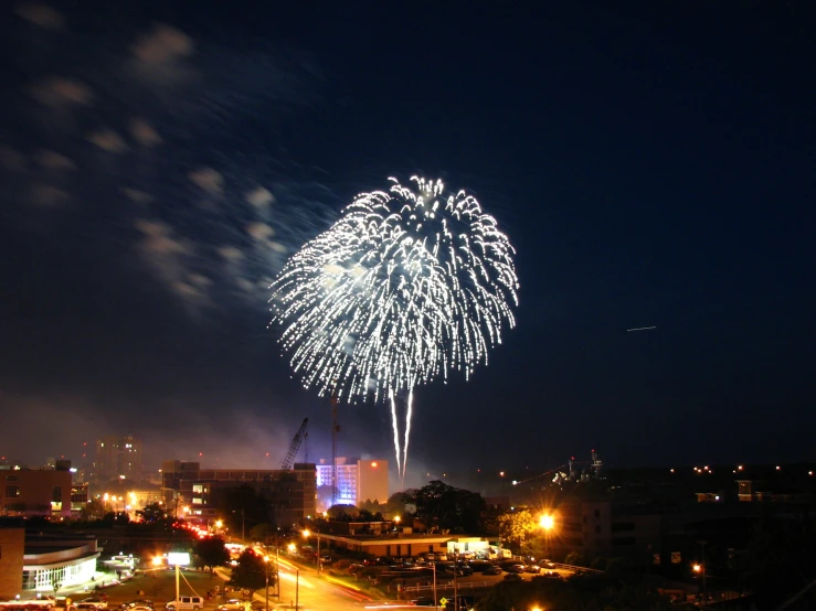 fireworks on top of a tall building with cars parked around it