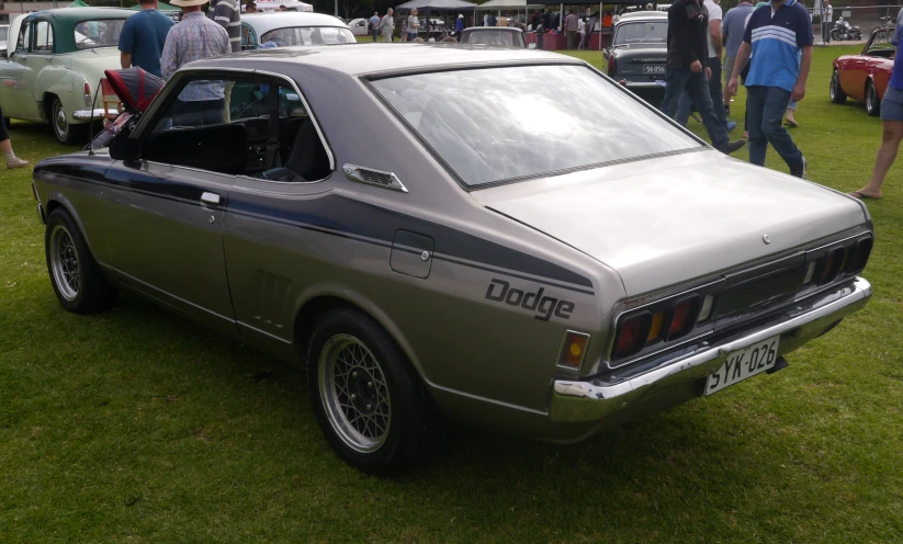 an old model grey car is parked on some grass