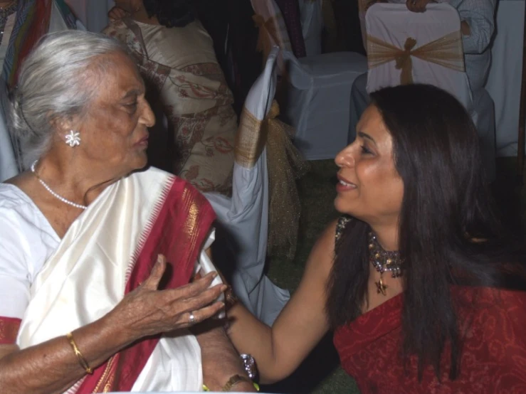 two ladies smile as they talk at a function