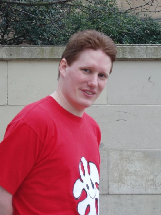 a man is in front of a cement wall and holding a red frisbee