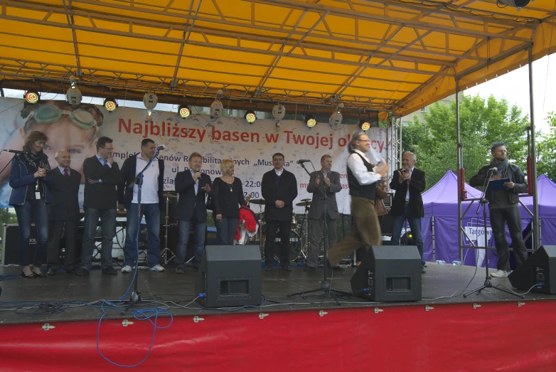 men are playing music on stage during an outdoor festival