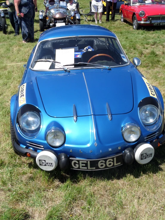 there is an old blue car parked in a grass field