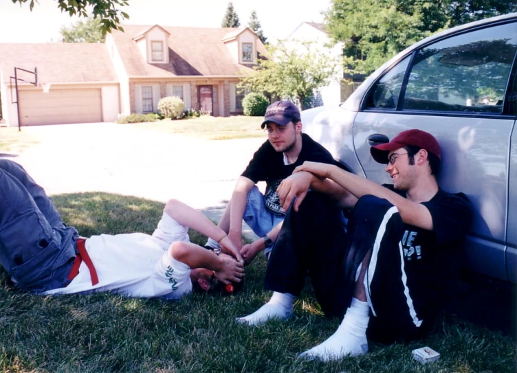 two boys are sitting by the car on the grass