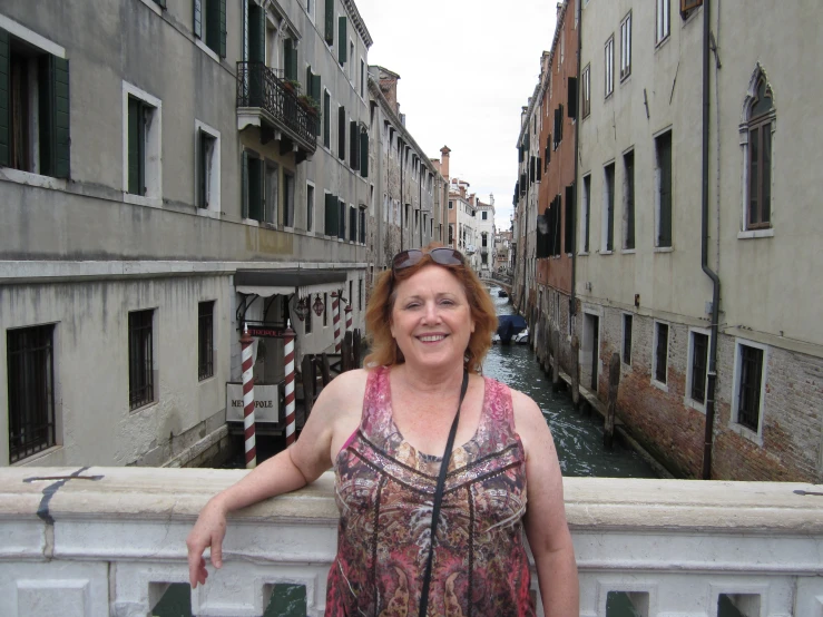 woman smiling with street lined in buildings, gondola above her