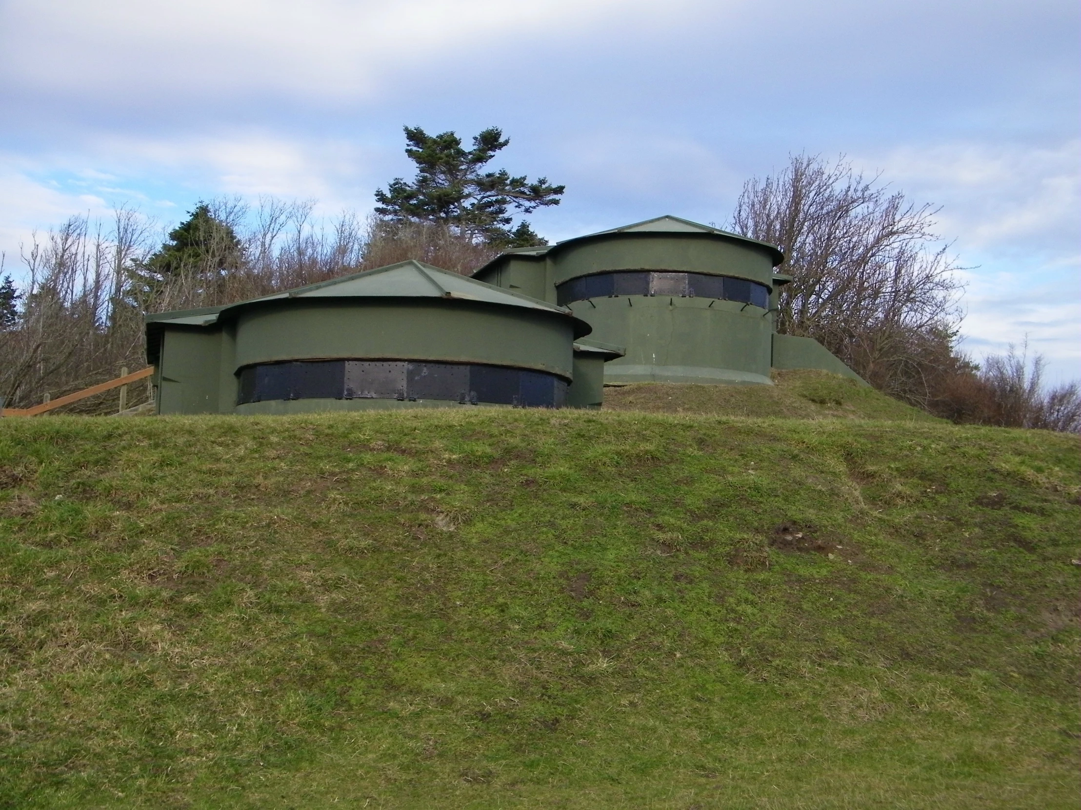 a green building sits on a grassy hill