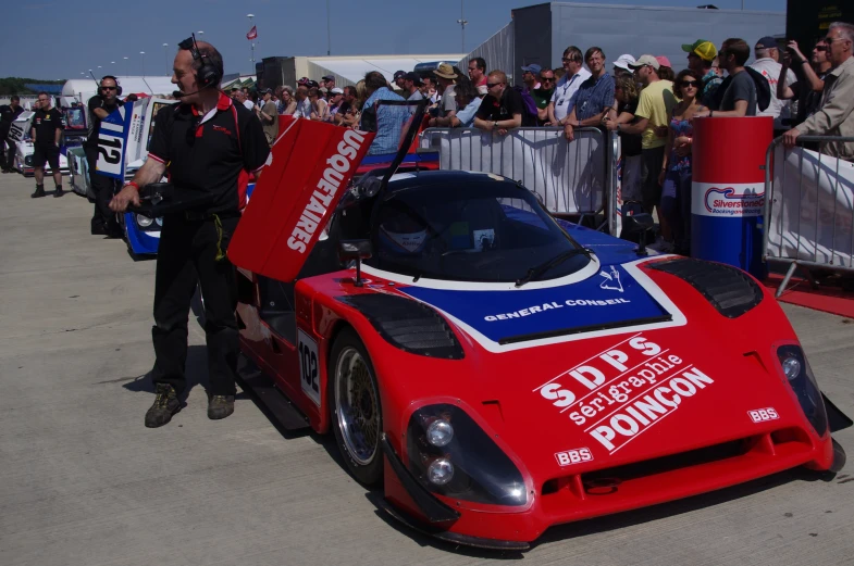 red car in front of a crowd with its doors open