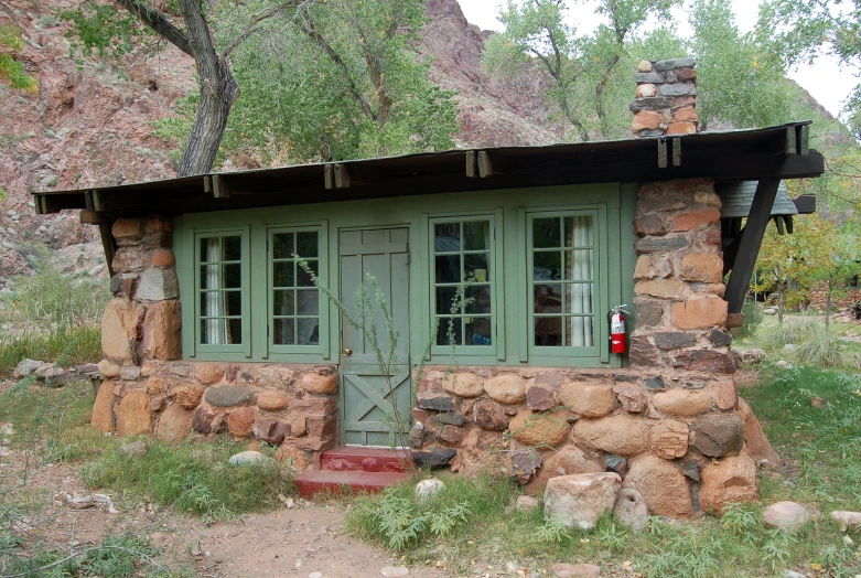 a green building with two doors and windows in a field