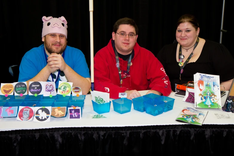 three people sitting at a table with some books and cards on it