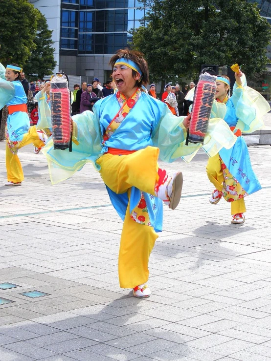 several people in colorful costumes holding onto asian fans