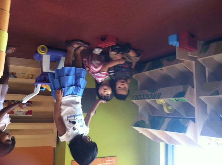 three children with toys and shelves in play room