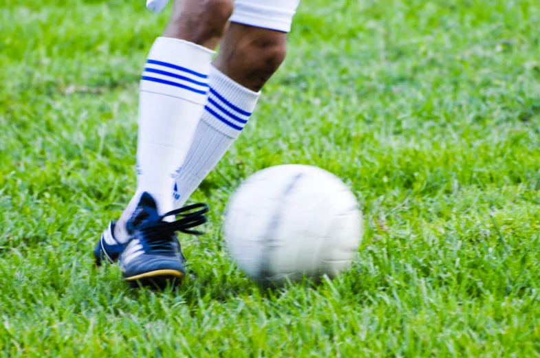 a soccer player kicks the ball during a game