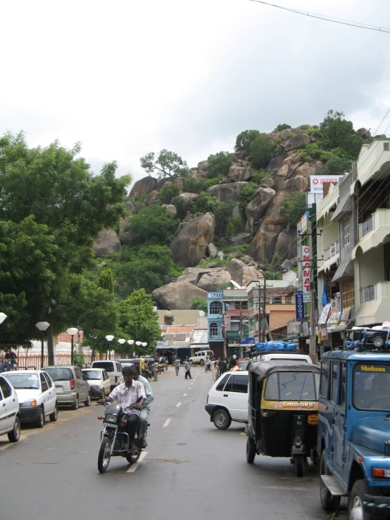 a man on a motorcycle passing a parking lot with vehicles