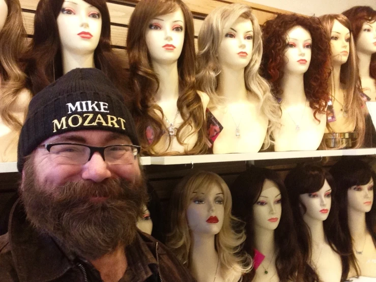 a bearded man in a store with lots of wigs