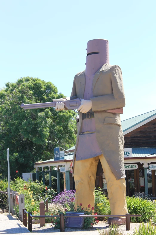 a statue of a man holding a rifle on the corner of a park