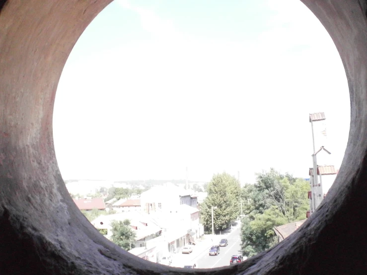 view through an old, rusty round window in a cement structure