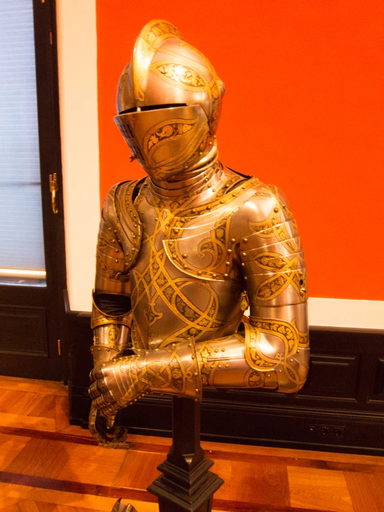 a gilded gold and black statue is sitting in front of a red wall
