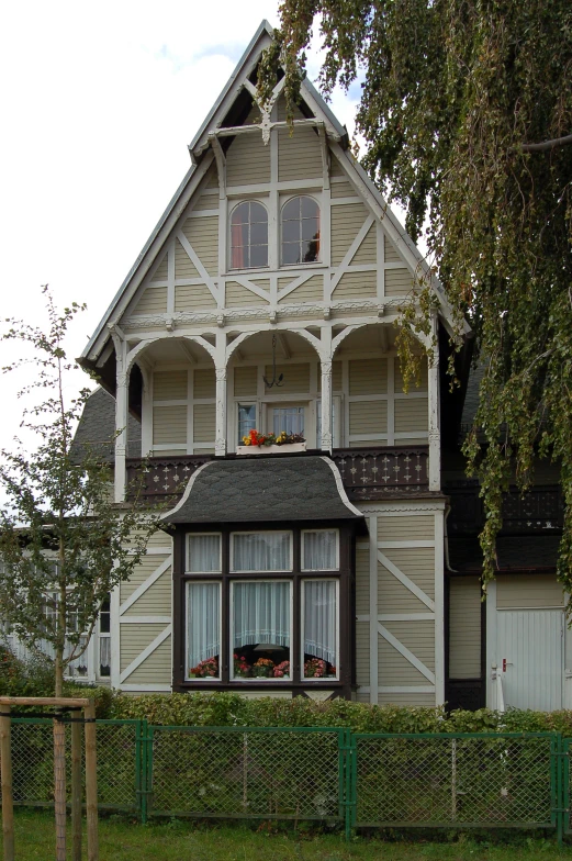 the side of a large house has an ornate window and balcony