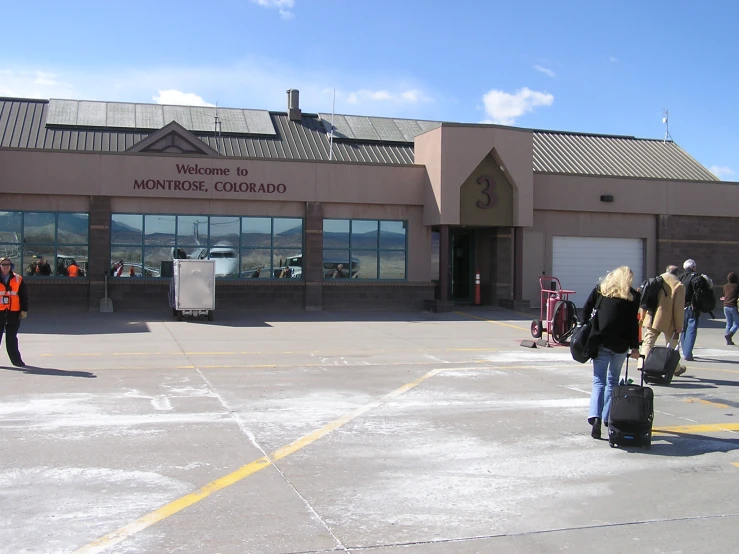 several people standing outside a building with luggage